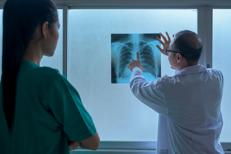 Doctor analysing x-ray film and showing to patient